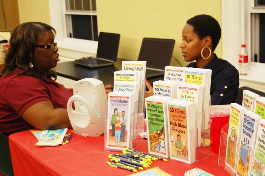 Yvette+Bailey+sits+at+a+table+at+the+Health+Fair+and+offers+pamphlets+and+tips.+The+first+85+students+that+attended+the+fair+received+a+free+five-year+health+screening.+%28Brittany+Moore%2FGuilfordian%29