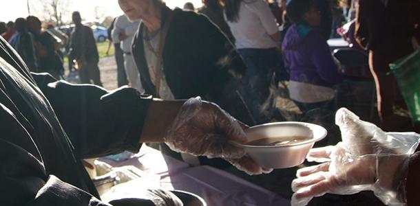 A volunteer shares a bowl of soup to an attendee of Church Under the Bridge last Spring. 
