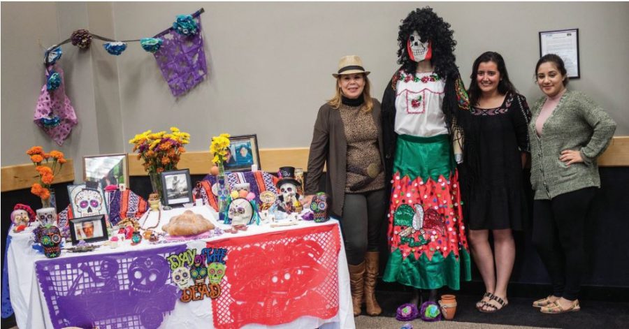 Latino Family Center staff Maria Harkins, Kelly Morales and Alejandra Vazquez stand beside an altar from Dia de los Muertos during the exhibition hosted by Caza Azul on Sat. Nov. 5.