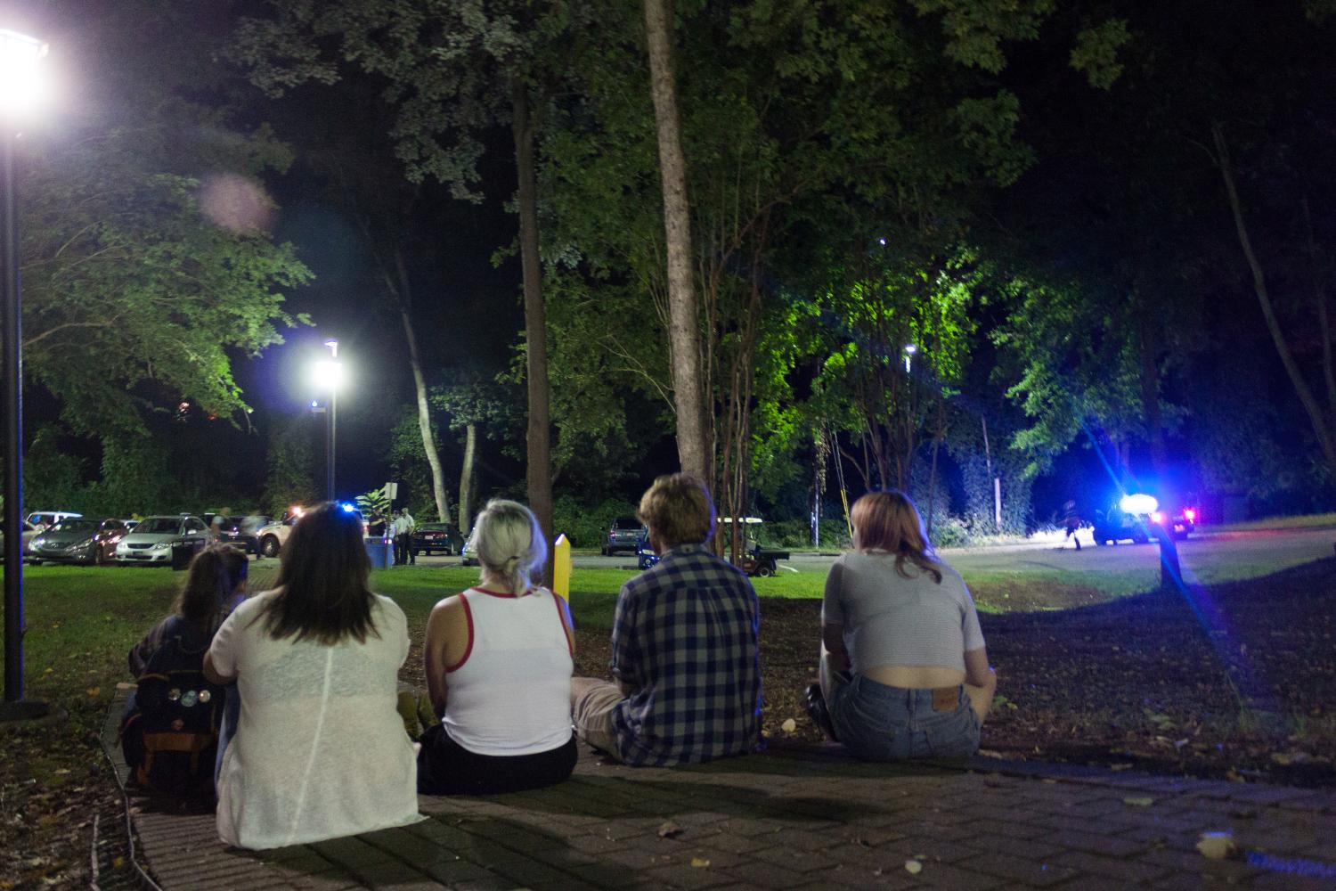 Five students sit on the pathway connecting the North Apartments to Elizabeth Fry Road as police conducted an operation at approximately 8:30 p.m. on Wednesday, Sept. 13, 2017.//Photo by Fernando Jimenez/The Guilfordian