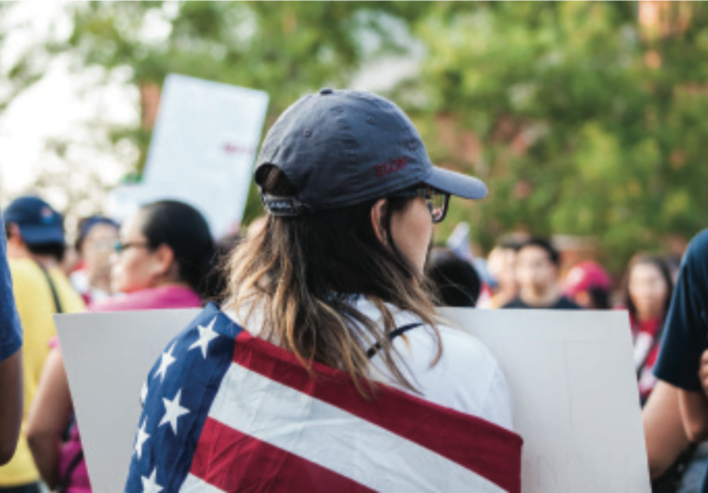 Chrisitina Gallegos, first-year student at Elon university, marched through downtown Greensboro wrapped in the United States flag to stand in solidarity with DACA receipients.// Photo by Fernando Jimenez/The Guilfordian