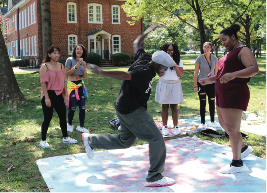 Assistant Professor of Art Antoine Williams and MiKayla Jones ‘19 dance at the Art on the Quad event on Wednesday afternoon, Sept. 20, 2017. Williams and Jones have shoe covers on their feet to decorate the large canvas with chalk as they dance. // Photo by Abigail Bekele/The Guilfordian