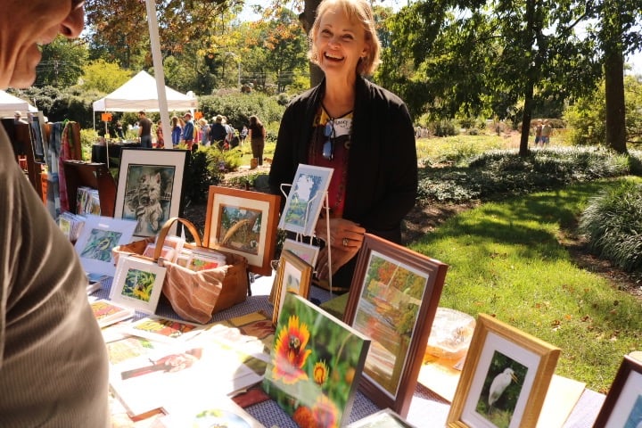 Artist Nancy Seay laughs as she talks to an attendee about her art, which were framed paintings and photographs of plants and animals that can be seen in the Greensboro environment.