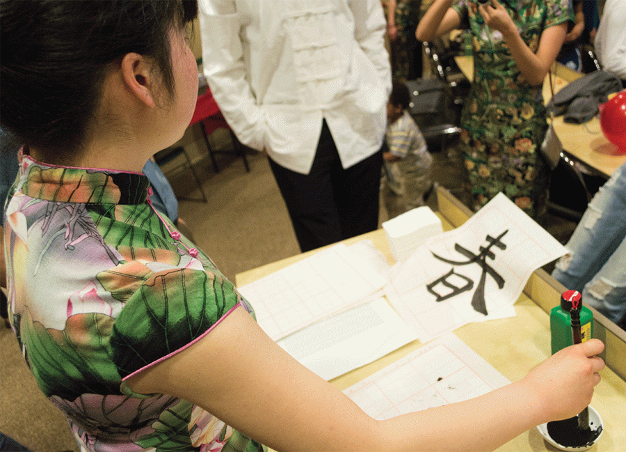 Junior Risa Suzuki shows attendees how to write traditional Chinese characters on parchment during the Chinese New Year celebration.// Photo by Christopher Perez/The Guilfordian