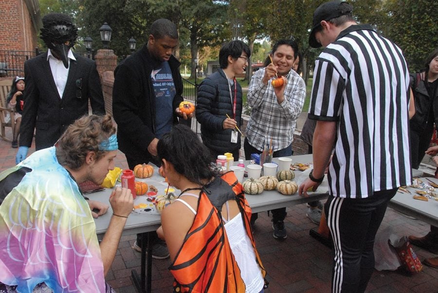 Students gather outside of Founders to paint pumpkins and celebrate Halloween. People came in costume and they were able to try different candy from different parts of the world. //Photo By Ezra Weiss/The Guilfordian 