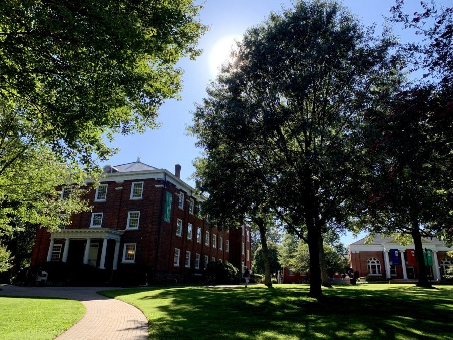 Sunlight filters through the trees onto the lawn in front of Duke Hall and Hege Library.