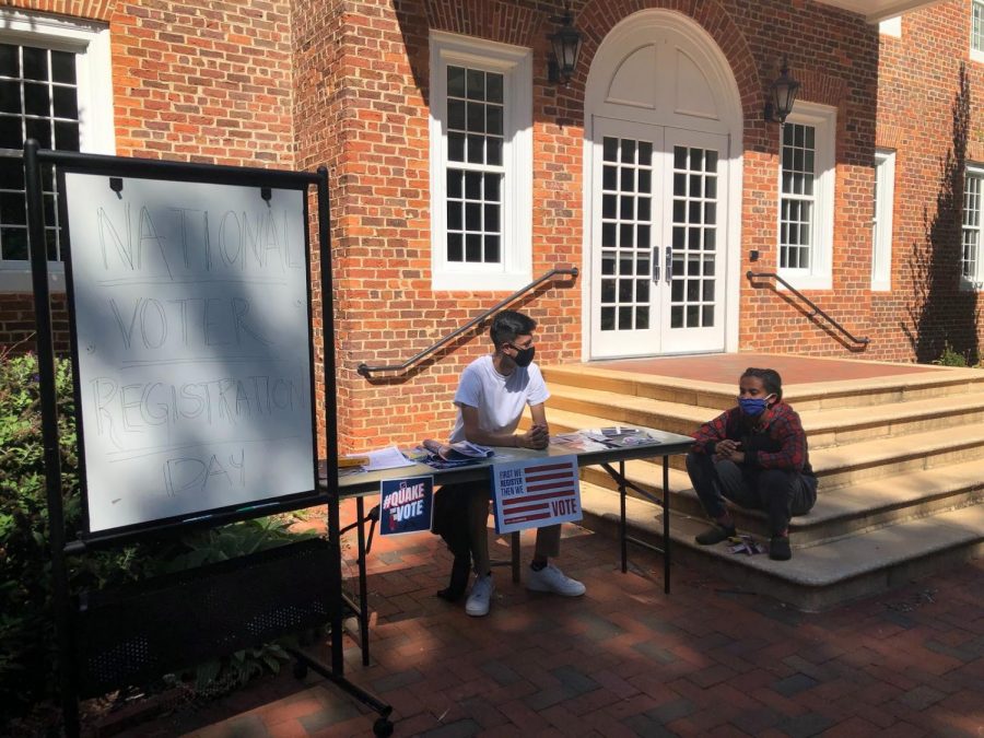 Kalkidan Miller and Isaac Collins wait tables outside Founders Hall to help students register to vote.