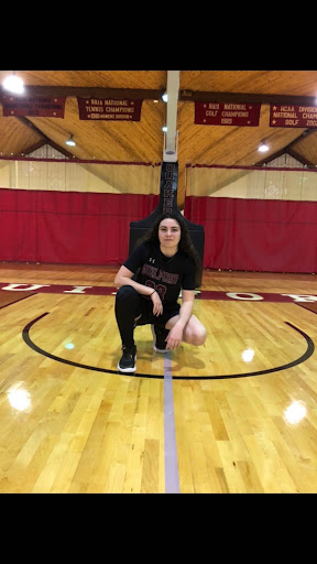 Alexis Woods kneeling at the center of the basketball court in the Ragan-Brown Field House.